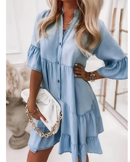 Light blue denim ruffle dress with button-down front and tiered sleeves styled with white clutch